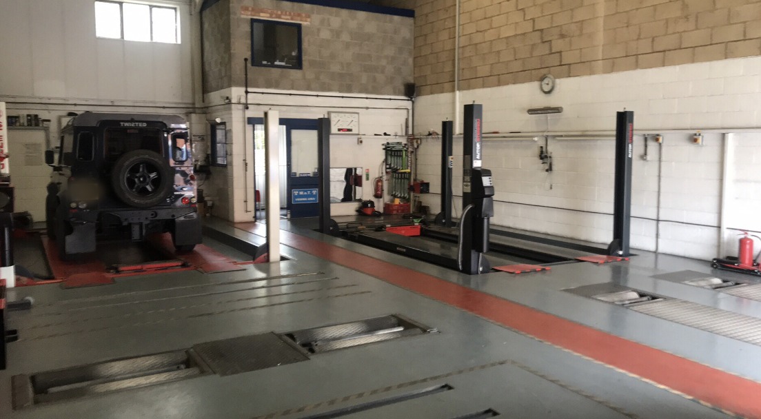 Inside our test hall: two-post lifts, roller brake tester set into the floor and a Land Rover Defender on the bay